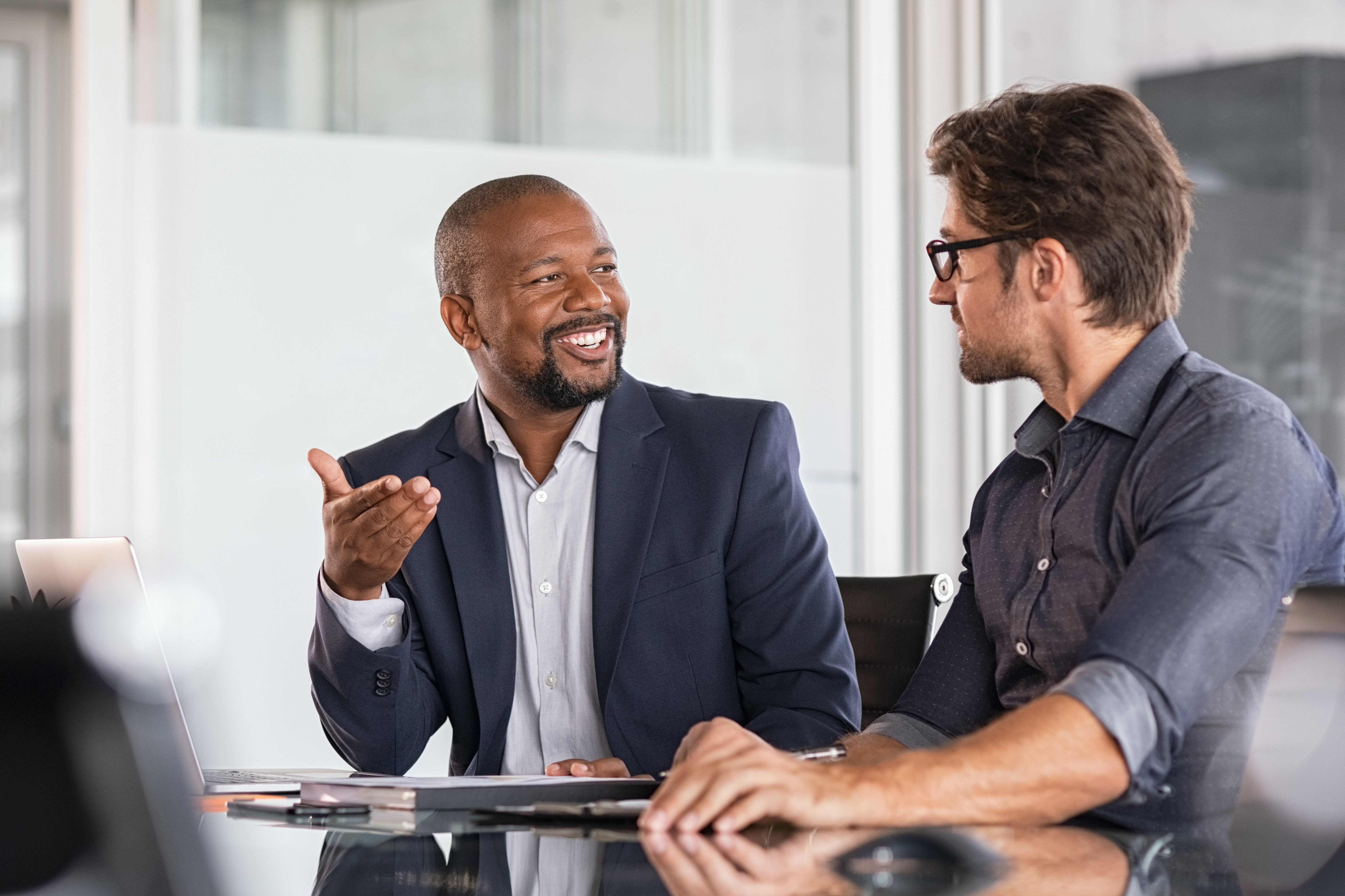 Two men at conference table talking