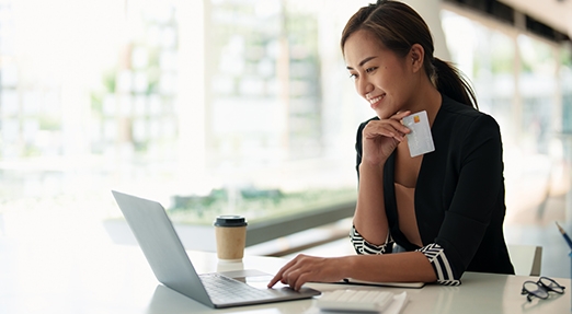 Female using laptop holding a banking or credit card