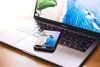 An open laptop with a phone on top of it, both with images of the beach.