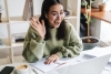 Young woman on the computer smiling and waving