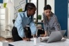 An image of two woman looking at an open laptop computer