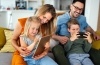 Family of 4 smiling while using a phone and tablet